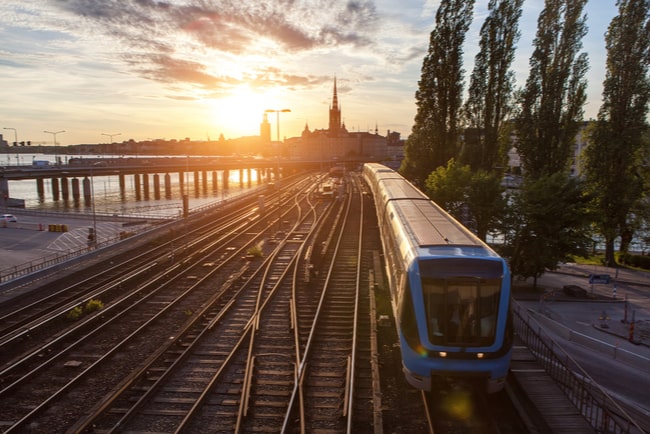 Tunnelbanetåg på räls i solnedgången.