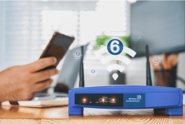 wifi 6 router med person med smartphone och dator i bakgrunden